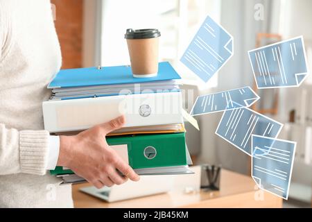 Man with stack of documents and digital files in office Stock Photo