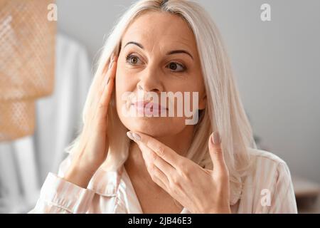 Morning of mature woman giving herself facial massage at home Stock ...