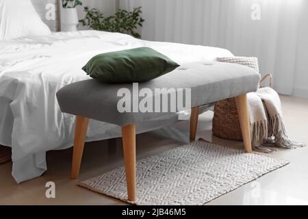 Soft bench with pillow near bed in light room Stock Photo