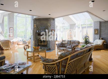 Rattan furniture in opened concept living room with varnished hardwood floor inside modern home. Stock Photo
