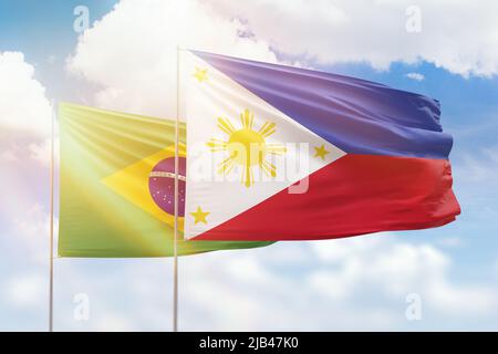 Philippines and Brazil flags waving together in the wind on blue cloudy ...