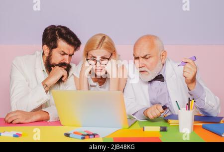 Group of business people analyzing reports on computers. Busy diverse millennial team discussing project, brainstorming at workplaces. Stock Photo