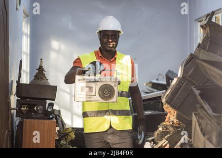 Mark Oluoch an electronic waste worker with Waste Electrical and Electronic Equipment Centre (WEEE Centre) displays an old radio cassette player at an e-waste collection center in Nakuru before it is later transported to Nairobi for recycling. Kenya generates about 11,000 metric tonnes of electronic waste every year, most of this waste has been found to contain harmful chemicals like lead, mercury, and phosphorus. There are calls to increase collection and recycling rates for both electronic and plastic waste to safeguard the environment and public health. Stock Photo