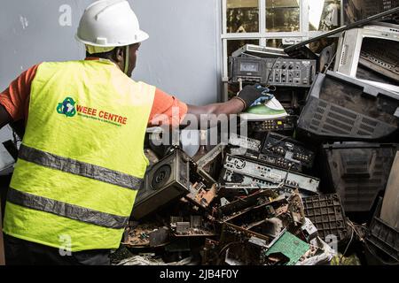 Mark Oluoch an electronic waste worker with Waste Electrical and Electronic Equipment Centre (WEEE Centre) sorts electronic waste at an e-waste collection center in Nakuru before it is later transported to Nairobi for recycling. Kenya generates about 11,000 metric tonnes of electronic waste every year, most of this waste has been found to contain harmful chemicals like lead, mercury, and phosphorus. There are calls to increase collection and recycling rates for both electronic and plastic waste to safeguard the environment and public health. Stock Photo