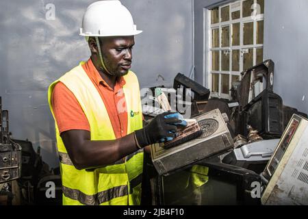 Mark Oluoch an electronic waste worker with Waste Electrical and Electronic Equipment Centre (WEEE Centre) dusts off an old radio at an e-waste collection center in Nakuru before it is later transported to Nairobi for recycling. Kenya generates about 11,000 metric tonnes of electronic waste every year, most of this waste has been found to contain harmful chemicals like lead, mercury, and phosphorus. There are calls to increase collection and recycling rates for both electronic and plastic waste to safeguard the environment and public health. Stock Photo