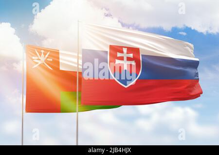 Sunny blue sky and flags of slovakia and oman Stock Photo