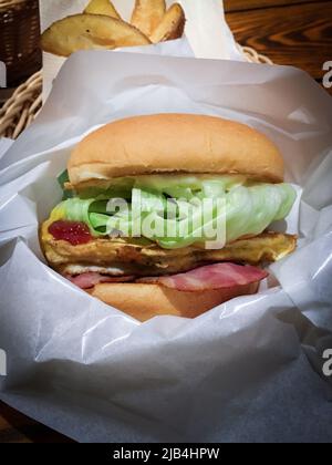Delicious omelette, lettuce and bacon hamburger in wrapping paper in restaurant in Kumamoto, Japan. Stock Photo