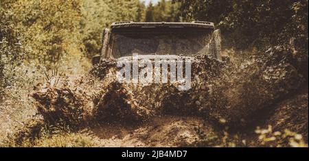 Off road sport truck between mountains landscape. Offroad vehicle coming out of a mud hole hazard. Drag racing car burns rubber. Extreme. Jeep crashed Stock Photo