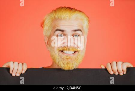 Man holding a blank billboard isolated on background. Business man holding a blank banner and looking down to copy space. Stock Photo