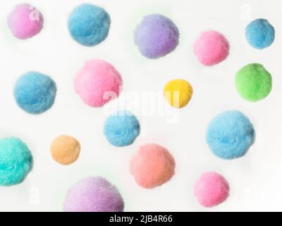 random arrangement of small fluffy pastel colored pom pom balls on a white background Stock Photo