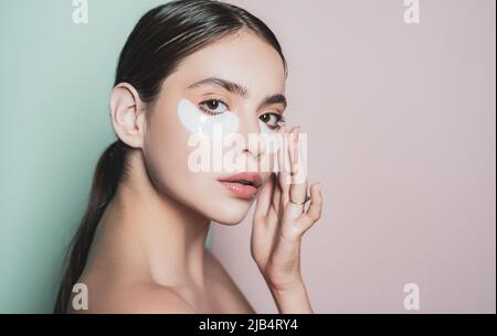 Beauty girl face with flakes under the eyes. Womans flakes. Patches under close eyes for woman. Young girl with patches under eyes from wrinkles. Stock Photo