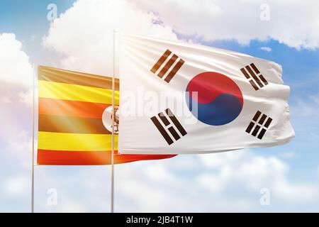 Sunny blue sky and flags of south korea and uganda Stock Photo