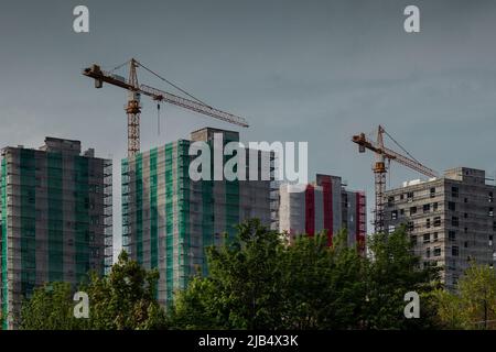 Construction site of a city block buildings or skyscrapers. Visible cranes working on the four buildings that are about to be built. View from behind Stock Photo