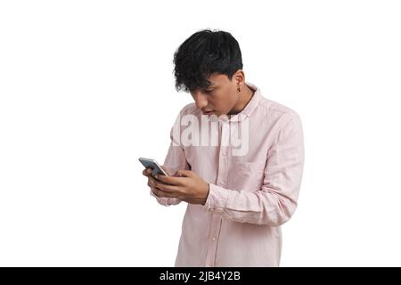 Young peruvian man surprised using the smartphone, isolated. Stock Photo