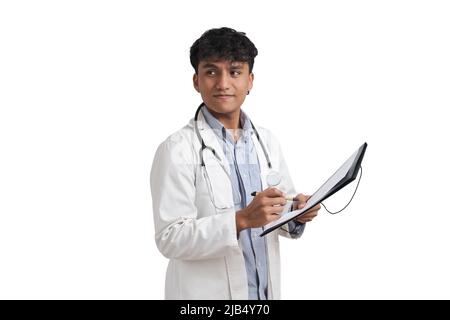 Young peruvian male doctor writing a medical report on a folder, isolated. Stock Photo