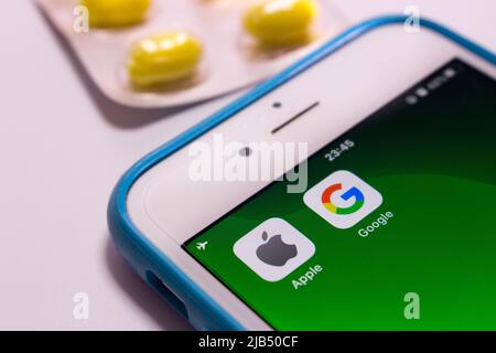Kumamoto, Japan - May 7 2020 : Concept image of Apple & Google logo on iPhone screen with pills on white background. Stock Photo