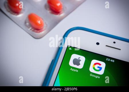 Kumamoto, Japan - May 7 2020 : Concept image of Apple & Google logo on iPhone screen with pills on white background. Stock Photo