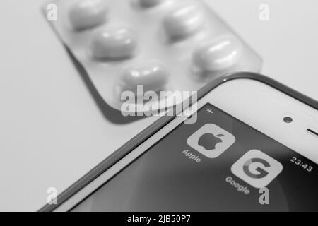 Kumamoto, Japan - May 7 2020 : Concept image of Apple & Google logo on iPhone screen with pills in monochrome. Stock Photo