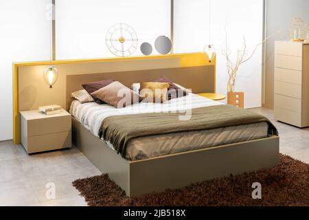Interior of modern bedroom with soft bed and assorted abstract decorations illuminated with sunlight Stock Photo
