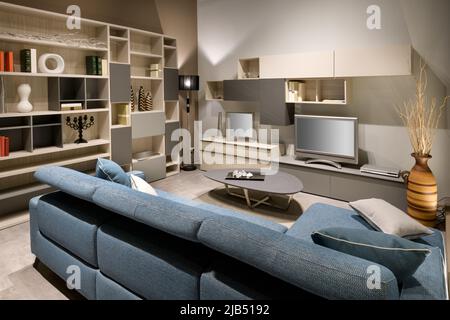 Comfortable sofa located near shelves with decorations and TV in modern living room at home Stock Photo