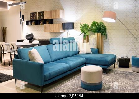 Comfortable blue chair located near dining zone in contemporary living room illuminated with lamps Stock Photo