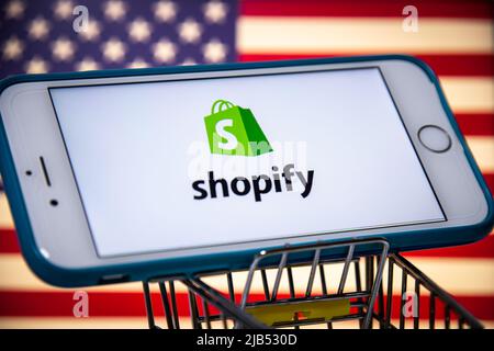 Logo of Shopify, a Canadian multinational e-commerce (online stores & retail point-of-sale systems) company, on iPhone in shopping cart with US flag Stock Photo