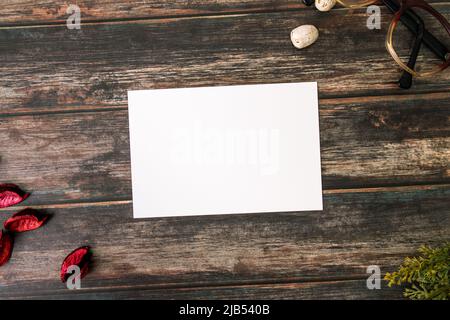 Feminine desktop mockup with blank white paper card, vintage eyeglass, branches and Pot Pourri on brown shabby table. Stylish retro concept Stock Photo