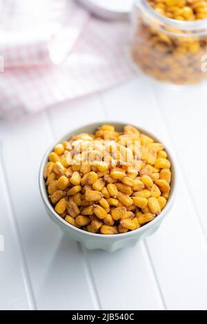 Roasted salted corn snack in bowl on a white table. Stock Photo