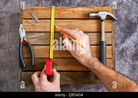 Measurements using roulette sizes for repair. Hands with tool. Set of tools for home repair. Hammer, pliers, nails, nuts. Stock Photo