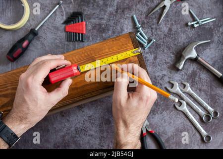 Measurements using roulette sizes for repair. Hands with tool. Set of tools for home repair. Hammer, pliers, nails, nuts. Stock Photo
