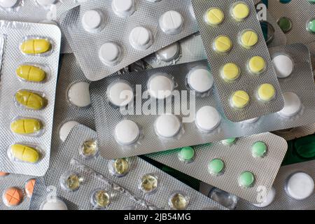 Pile of various pills with home medicine cabinet on blue background, painkillers, colored pills, medicine in tablets Stock Photo