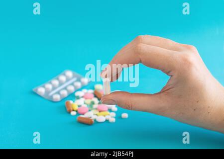 Get the pills out of the blister. Pill in hand. Pills and pills on a blue background. Medical tablets: analgesics, antipyretics. Taking medication. Stock Photo