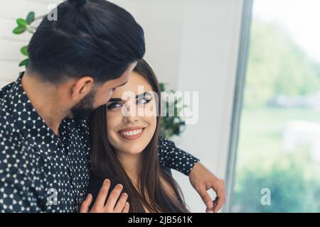 Passionate affectionate interracial young couple hugging and looking at each other with love. Indoor shot in a modern white apartment. High quality photo Stock Photo
