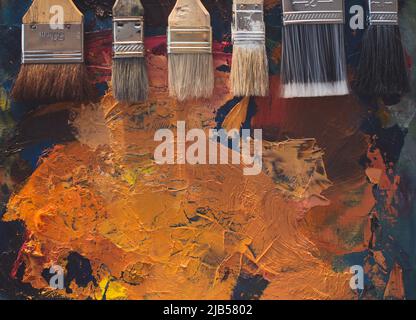 Paintbrush set lying on an old palette with oil paint brushstrokes top view photo Stock Photo