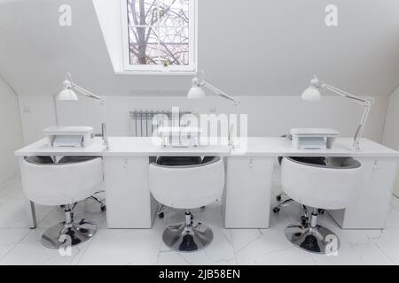 Stylish modern nail salon in bright colors. Manicure workplace with three table lamps and a window in the background Stock Photo