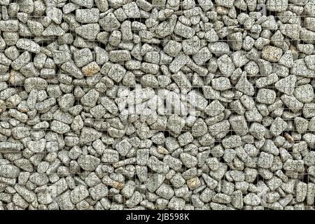 Textured background of a stone wall with iron netting. Stone wall in wire frame. Stock Photo