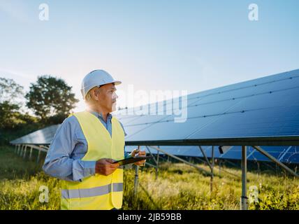 Male engineer using tablet to inspect the solar panels. Eco energy concept Stock Photo