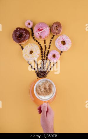 various donuts on coffee beans like balloons on a yellow background Stock Photo
