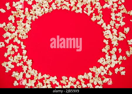 Popcorn on a red background, corn kernels top view. Stock Photo