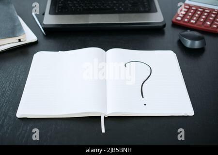 Question mark in a notepad on the background of a laptop and a calculator Stock Photo