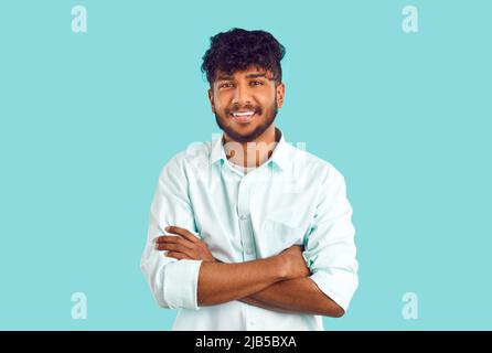 Portrait of happy young Indian or Arab man in shirt standing with his arms folded and smiling Stock Photo
