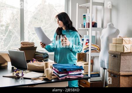 Young woman tailor fashion designer dressmaker using laptop in seamstress studio Stock Photo