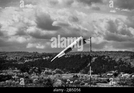 Wind direction indicator near a landscape at sunset with dramatic cloud formations Stock Photo