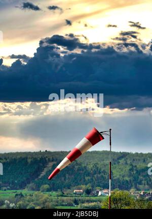 Wind direction indicator near a landscape at sunset with dramatic cloud formations Stock Photo