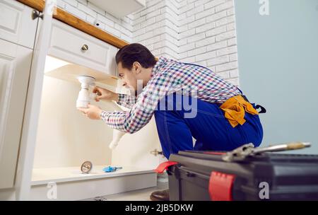 Plumber fixing some problems with the kitchen sink, repairing pipes or unclogging the blockage Stock Photo