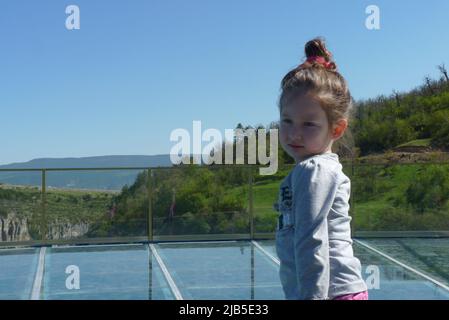 Young Child Outdoors with Light-Colored Hair Tied Back, Wearing Light Gray T-Shirt Stock Photo