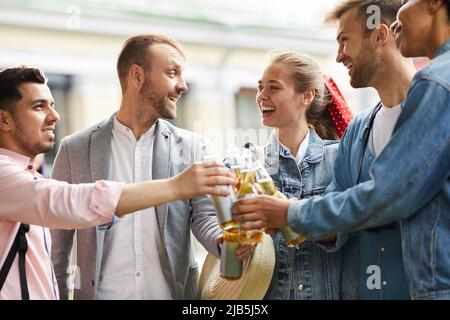 Group of excited young friends in casual clothing standing together and having fun with beer Stock Photo