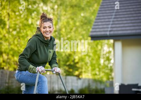Woman working with lawn roller in the garden Stock Photo