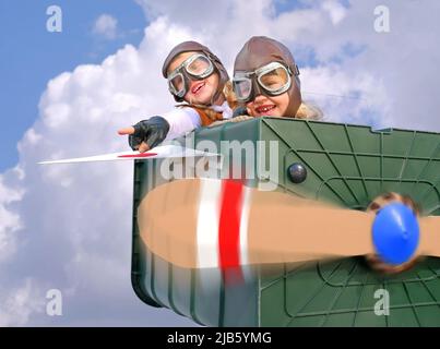 Twin sisters sit at the controls of their imaginative airplane.  They play pilot and co-pilot with an airplane made  from items found in their garden. Stock Photo