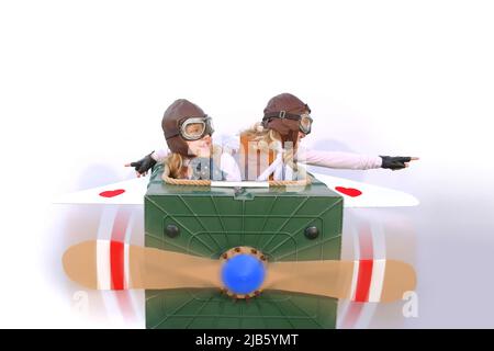 Twin sisters sit at the controls of their imaginative airplane.  They play pilot and co-pilot with an airplane made  from items found in their garden. Stock Photo